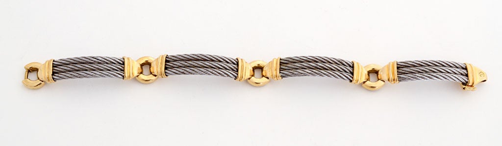 Tailored bracelet by Swiss designer Philippe Charriol in stainless steel and 18 karat gold. Measures 7 1/2