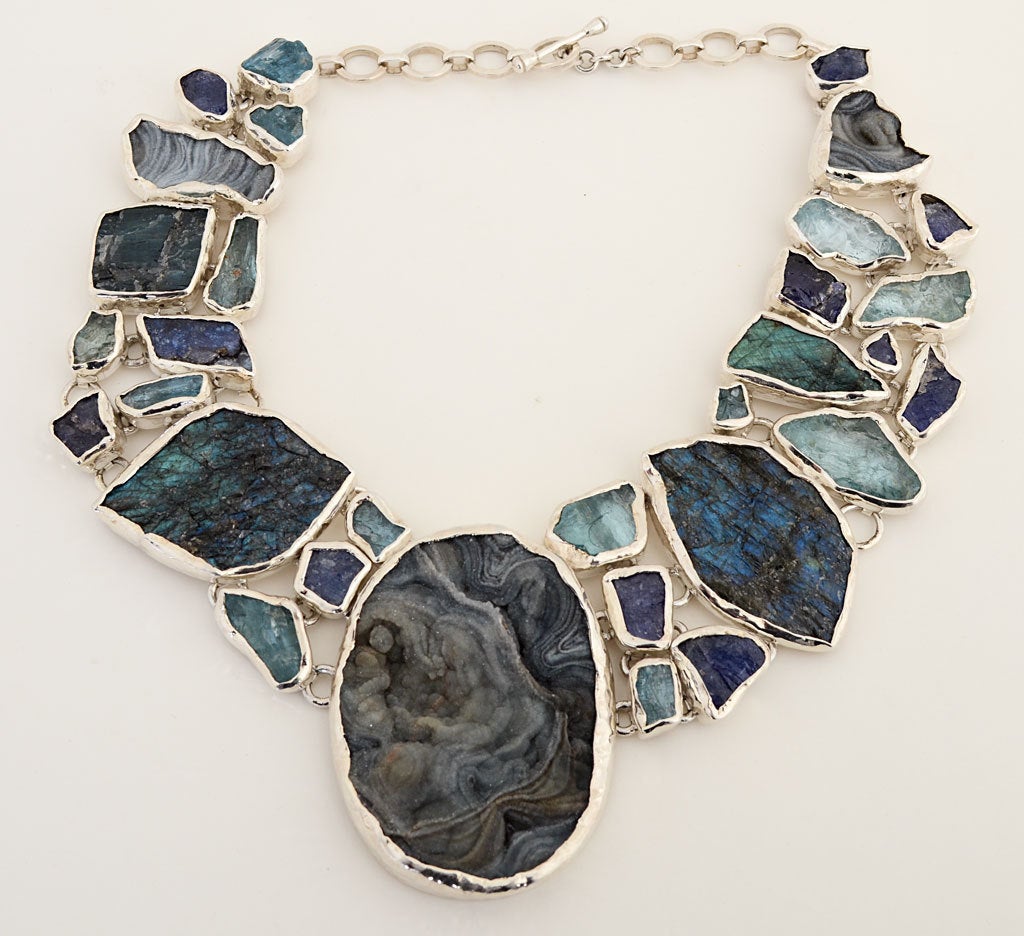 This one of a kind silver necklace combines desert rose; drusy; tanzanite and aquamarine into an amazing form. Both the colors and textures of the stones merge to make an dramatic statement. A toggle clasp allows the length to be adjusted. It is 