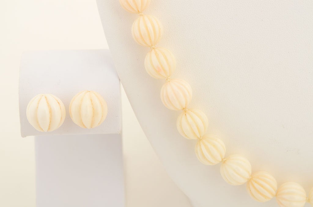 This lovely 23 inch necklace and matching earrings are made of melon carved white ivory. The beads are 11 mm with a fourteen karat gold clasp signed both Gump's and the makers initials MK. Earrings have post backs.