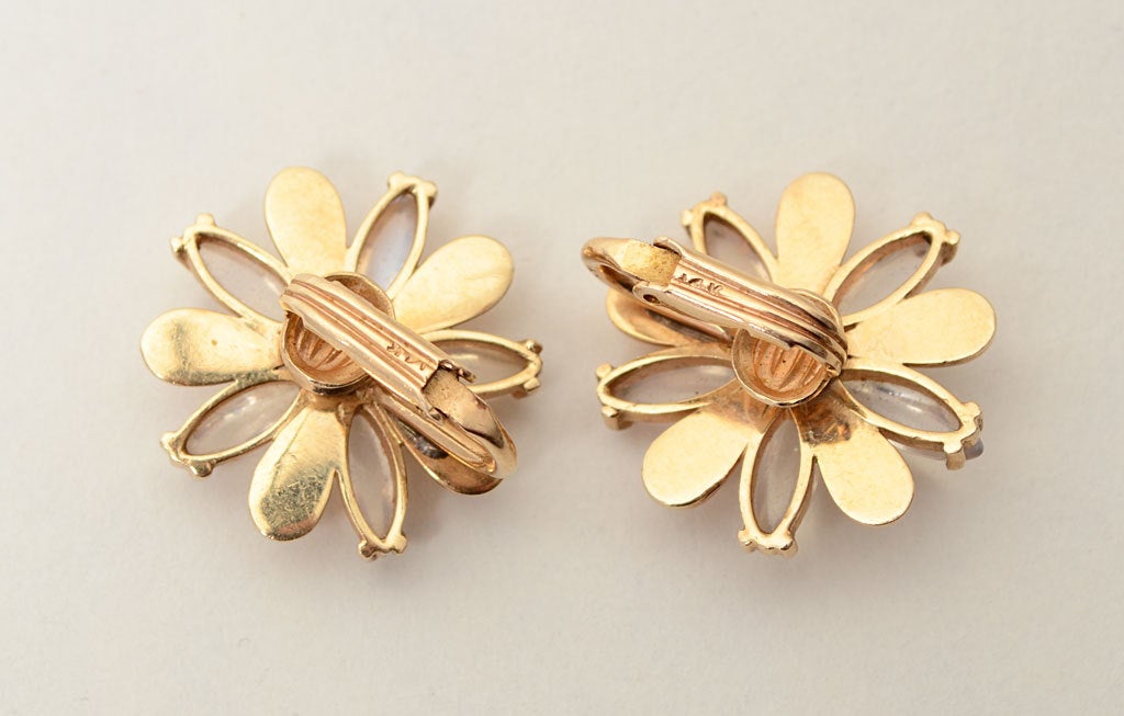 Retro stylized flower earrings with alternating petals of gold and moonstone centered with a sapphire. They measure 7/8" in diameter and have clip backs.