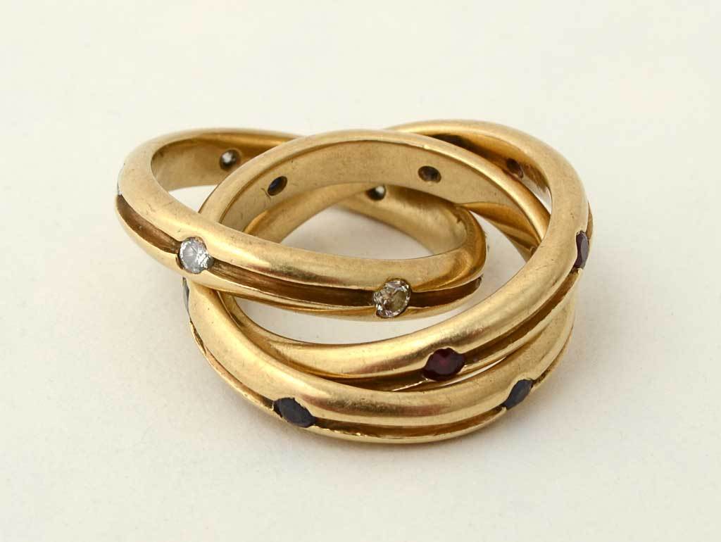 This unusual version of Cartier's Trinity Rolling Ring combines diamonds, rubies and sapphires. Each band has six stones. It is size 7.