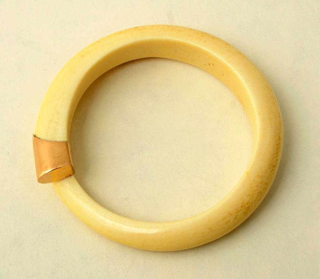 Ivory bangle bracelet with gold tips. Inside diameter measures 2 1/2