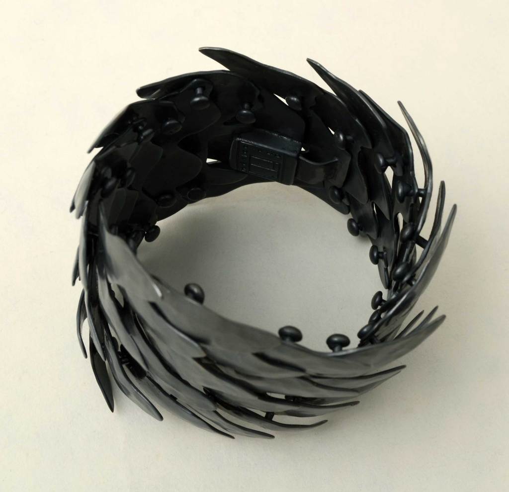Mexican architect, Eduardo Herrera has turned to jewelry making. His architecture background is evident in his metal creations. This wide bracelet that he describes as Scales, has a slightly Goth look due to the oxidized color. It is undulating in