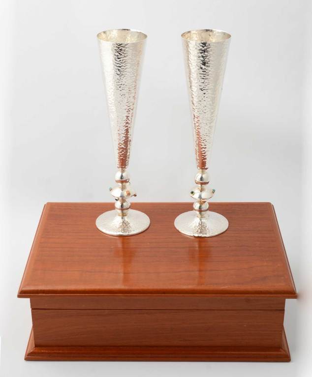 Very festive champagne flutes by Emilia Castillo in her Confetti pattern. The body and bases of the flutes are hammered silver. The middle part of the stem is set with malachite; lapis lazuli; turquoise; coral. and carnelian. There is a bell inside