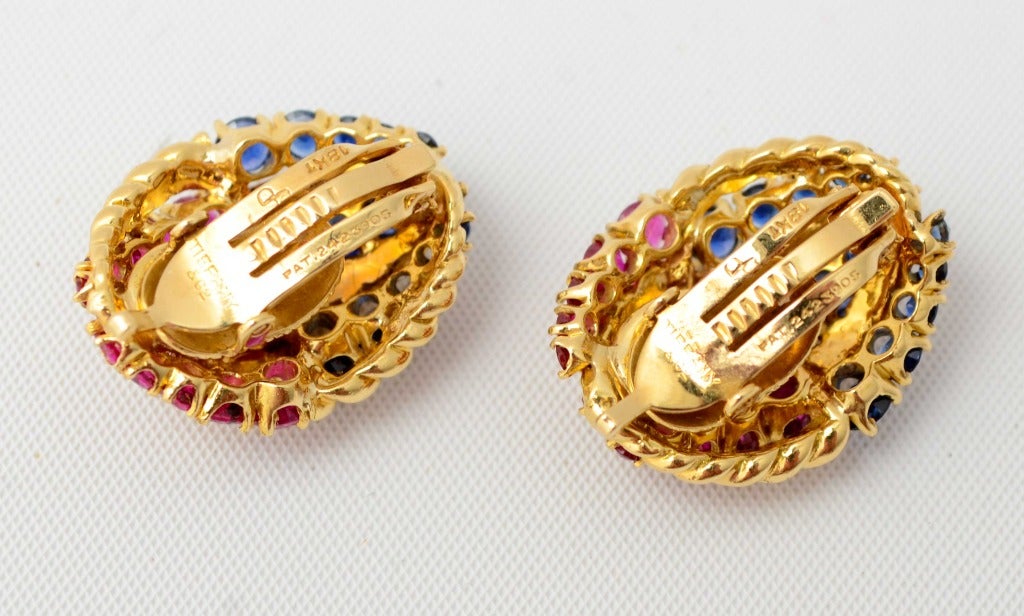 Beautifully detailed 18 karat gold earrings by Tiffany. Both the rubies and sapphires are graduated in size and are separated by ribs of twisted gold. They measure 1