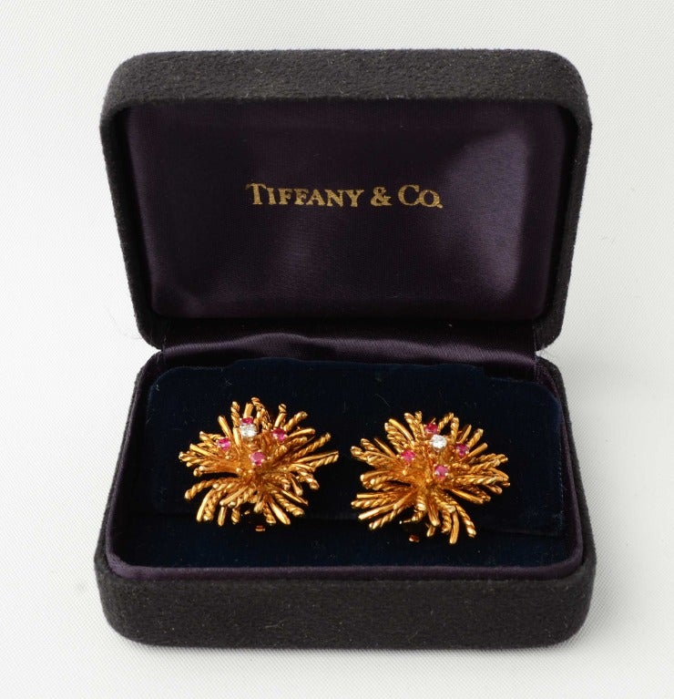 Tiffany earrings in eighteen karat gold with a center diamond and four rubies around it. The spokes alternate between smooth and rope twisted. Measure 1 1/16