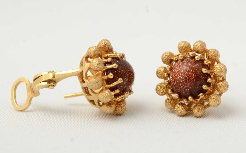 Eighteen karat and goldstone earrings in an unusual setting. Stones are set with alternating size prongs surrounded by textured balls. Measure 3/4