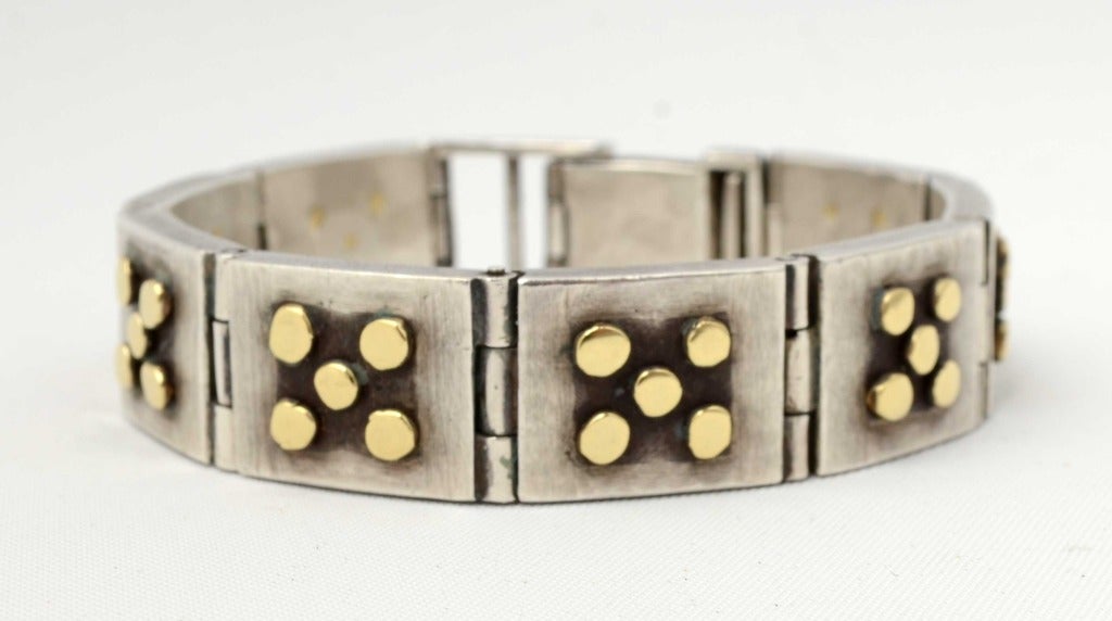 Sterling silver and 18 karat gold bracelet by jeweley designer, Laurence DeVries in a style he began in the early 1990's. It is extremely heavy weight with a subtly burnished texture to the silver background. DeVries's artistry and attention to