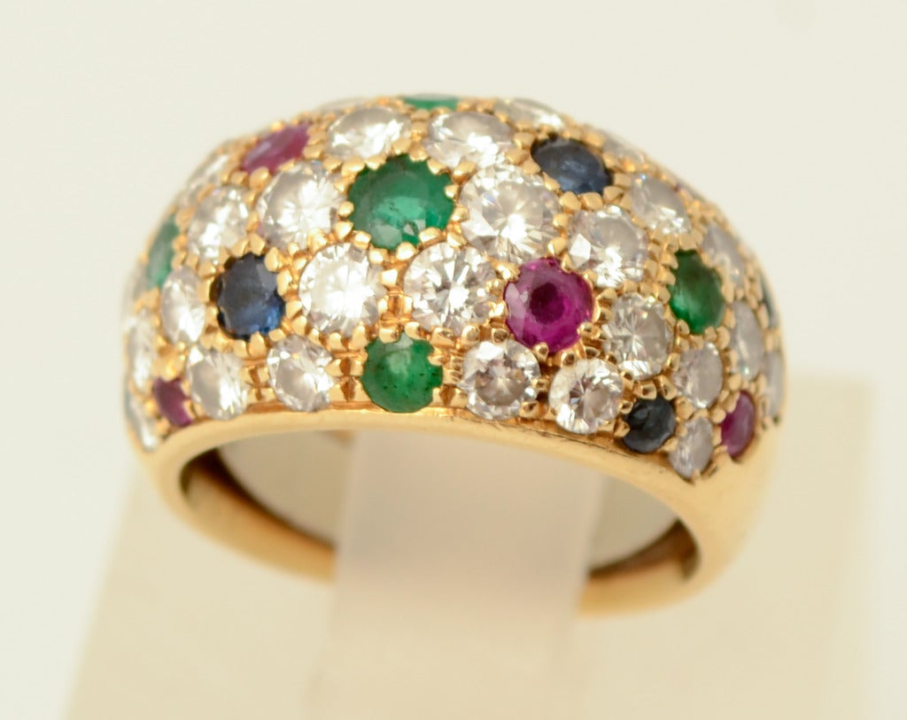 Elegant bombe ring by Van Cleef and Arpels with diamonds. Rubies; emeralds and sapphires are sprinkled throughout. The ring is size 5 but has a guard inside making it a 4 1/2. This can easily be removed. The front of the ring is 1/2