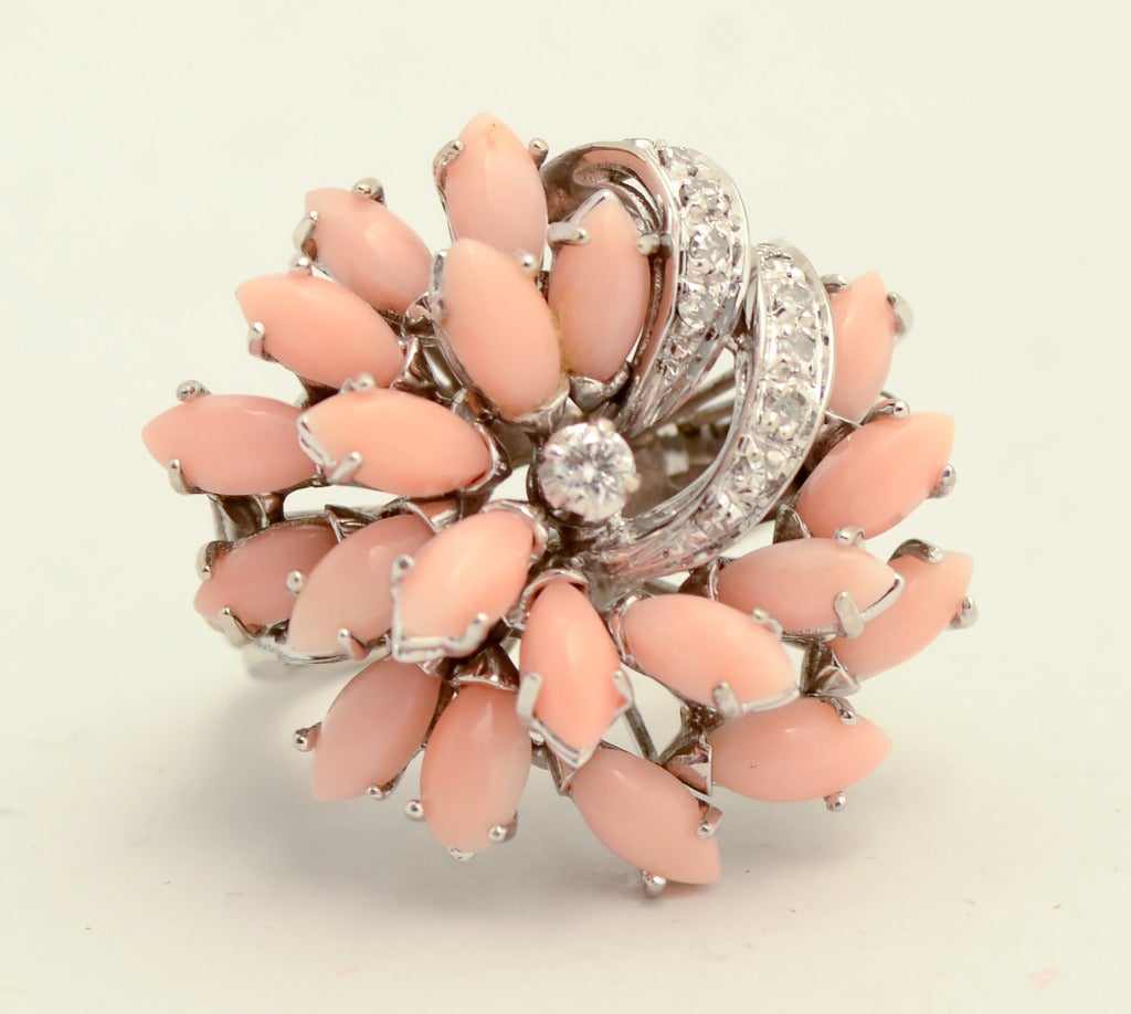Beautifully handmade ring of coral and diamonds set in 18 karat white gold. Placement of the diamonds gives the ring a nice swirling motion. 
The navette shaped coral stones are consistently angel skin in color. The middle thumbnail photo is most