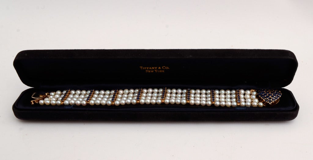 Both delicate and strong, pearl and sapphire bracelet by Tiffany set in 14 karat gold. Groups of pearls are separated by rows of sapphires with a sapphire heart clasp. The bracelet measures 7