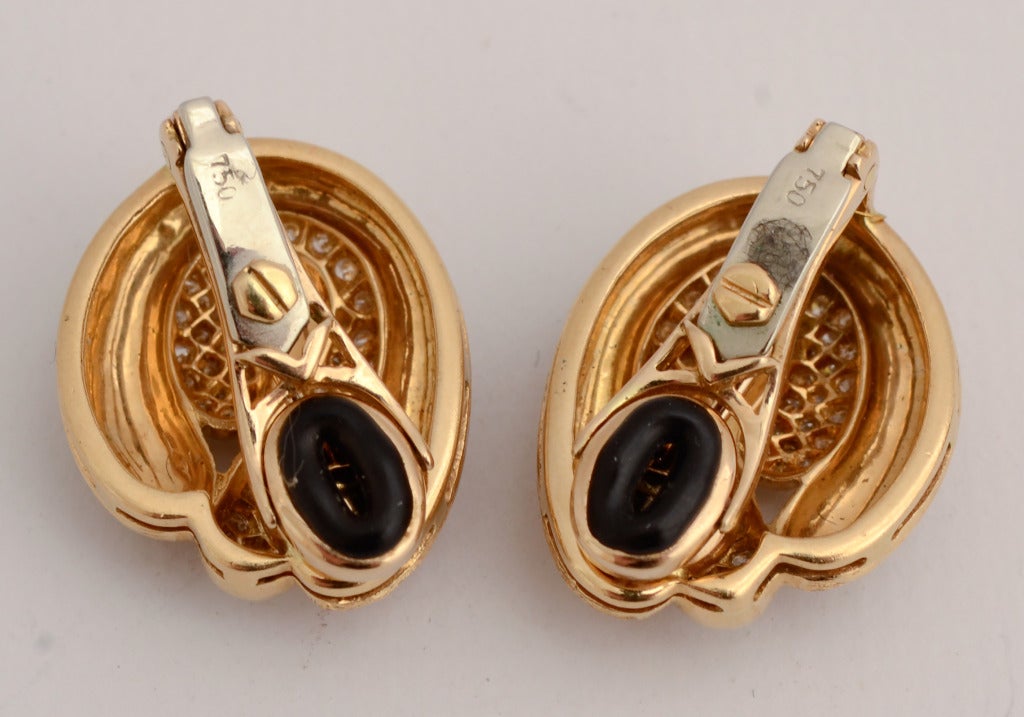 Brushed 18 karat gold earrings in the shape of an oval swirl, with diamonds echoing the shape  of the gold. Measure 1