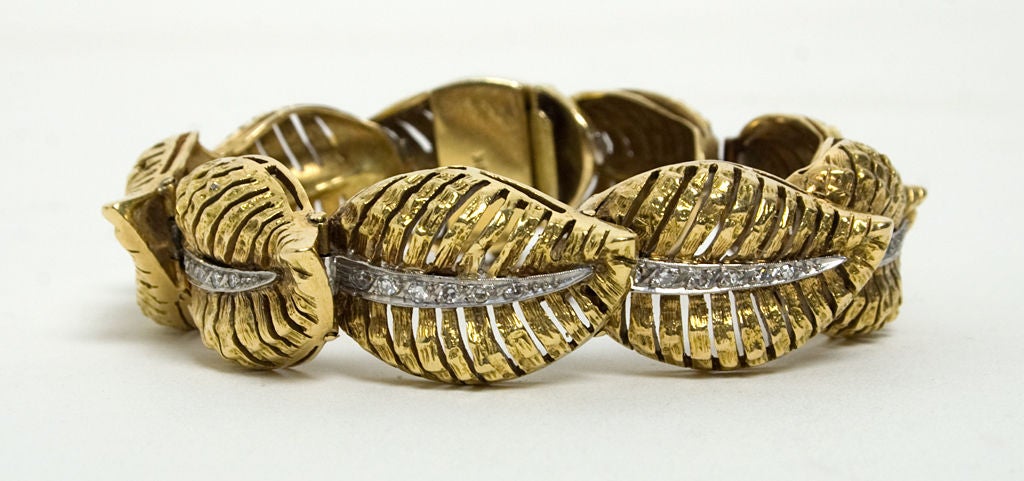 Three dimensional leaves are highlighted by diamond veins in this sculptural eighteen karat gold bracelet. Leaves are 5/8