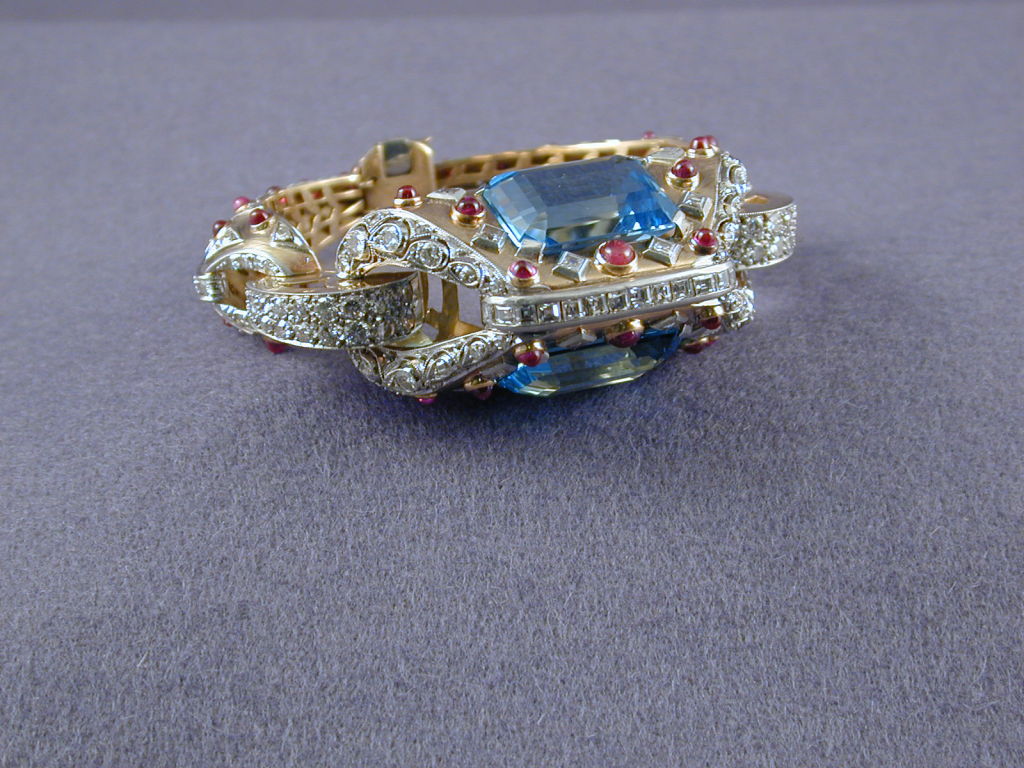 A superb and unusual Retro bracelet designed as an arch supported by a pair of fine aquamarines and enhanced with cabochon rubies and square diamonds attached to diamond pave stirrups forming the flexible bracelet.