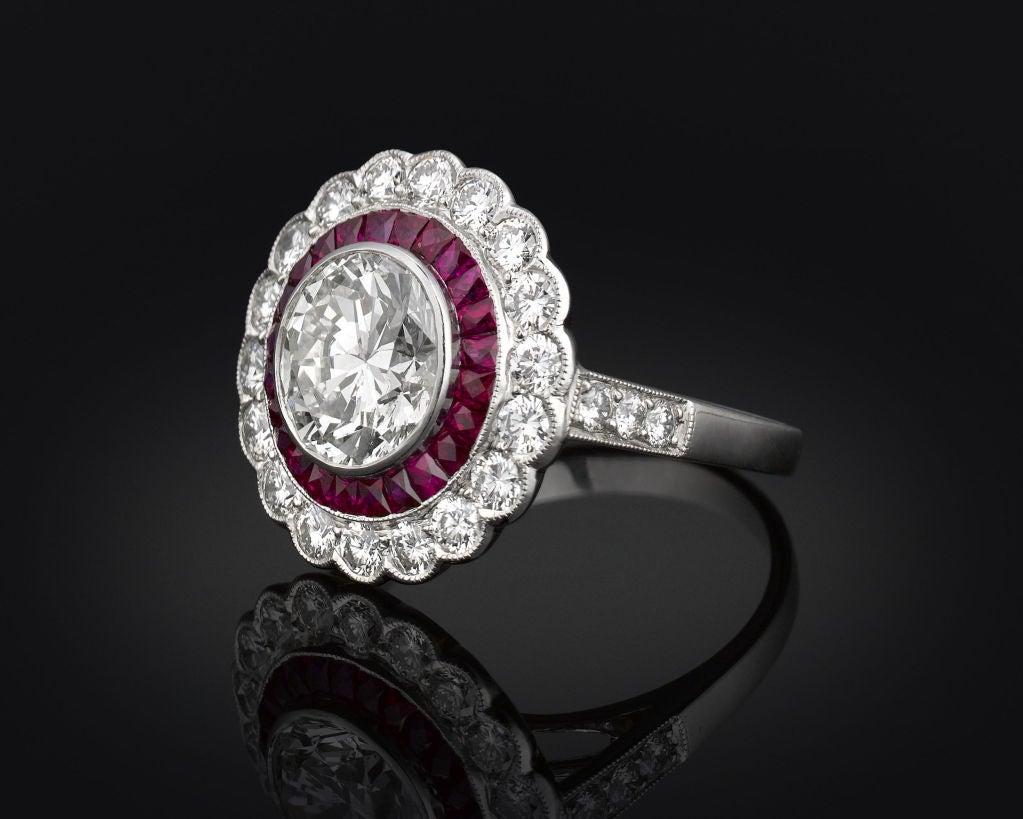 Bold and sophisticated, this period Art Deco ring is a symphony of diamonds and rubies. Crafted in a striking floral motif, this ring boasts a 2.15-carat Old European-cut diamond at its center, encircled by a band of channel-set rubies. Sparkling