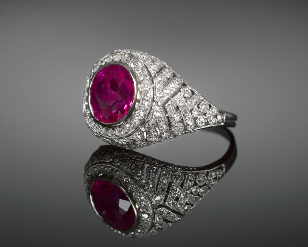A radiant Burma ruby commands attention at the center of this dazzling Edwardian ring. Set amid a host of diamonds in a stunning pierced dome platinum setting, this 2.80-carat cushion cut gem glimmers with the rare 