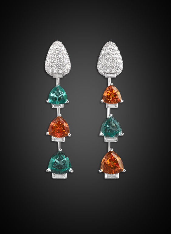 The fire and radiance of trillian-cut orange garnets and aqua-blue tourmalines make a daring statement in this pair of exquisite platinum drop earrings. The garnets weigh approximately 18.00, with the weight of the tourmalines estimated at 14.00