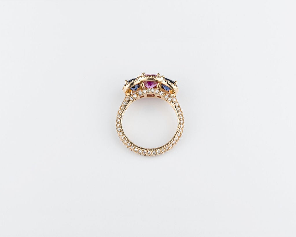 Captivating pink and blue sapphires smolder in this dynamic ring. The stunning 2.14-carat pink sapphire hails from Madagascar and is perfectly complemented by two blue Ceylon sapphires, which weigh 2.01 total carats. These rare gems are joined by