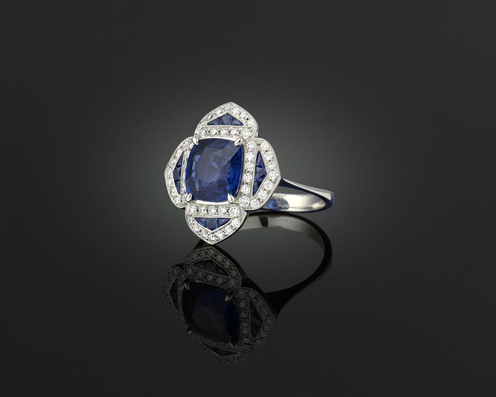 A fabulous cushion-cut sapphire takes place of honor in this dazzling Art Deco-style ring. The rich, velvety hue of this superb 3.01-carat gem is matched by calibrated sapphire accents weighing .75 carats, and complemented by .48 carats of diamonds