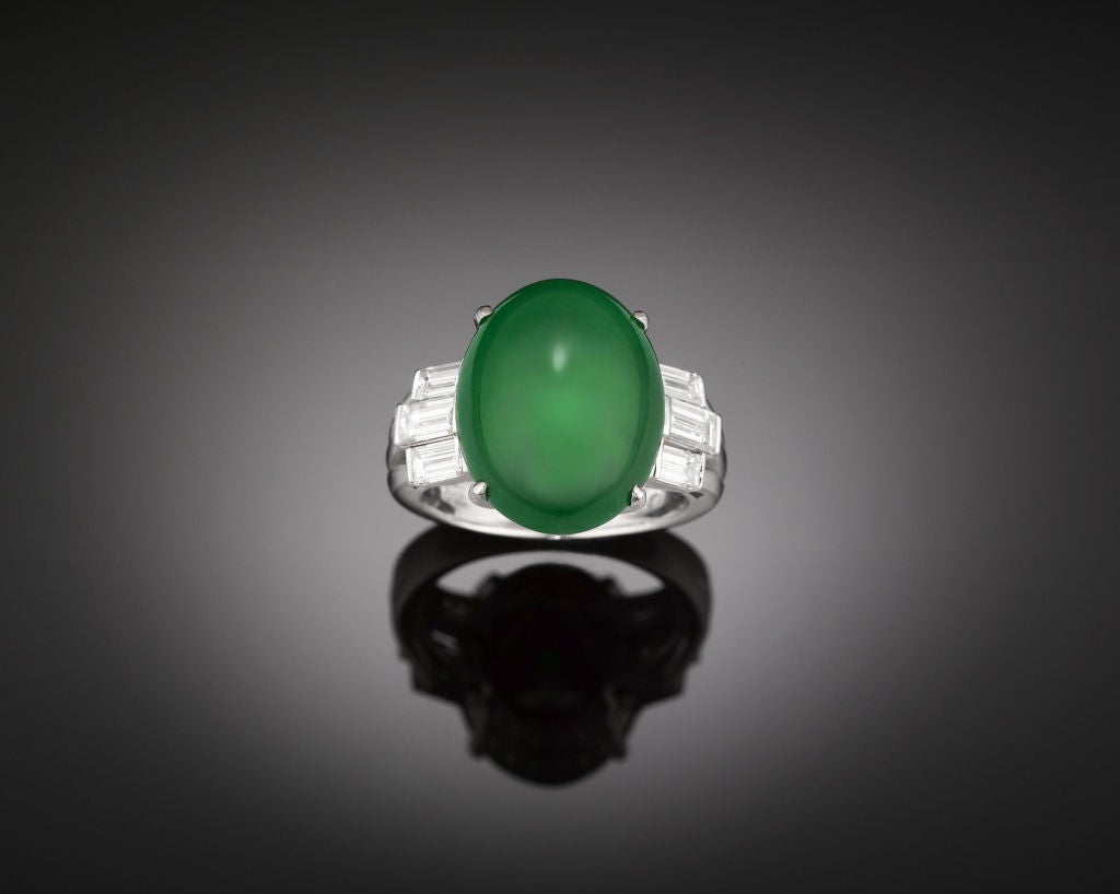 A rare Imperial jadeite commands attention in this captivating ring. This amazing stone's intense emerald hue and glassy translucence is beautifully complemented by six brilliant emerald cut diamonds. The diamond-studded 18K white gold band provides