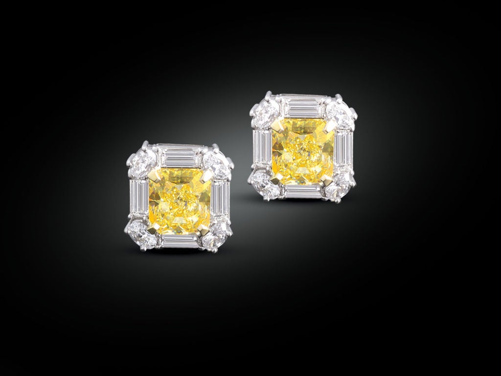 A striking pair of Natural Fancy Yellow diamond earrings weighing 6.07 total carats are encircled by 3.35 carats of white diamonds in these platinum and 18K yellow gold earrings. The yellow diamonds are GIA-certified Natural Fancy Yellow, VVS1 and