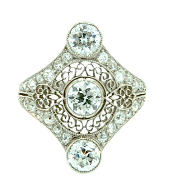 This unique Platinum and Diamond Ring has a beautiful lattice pattern surrounding three exceptional old mine Diamonds which weigh approximately 1 carat total. Smaller pave' set Diamonds accent the borders of this uniquely shaped Edwardian 3 stone