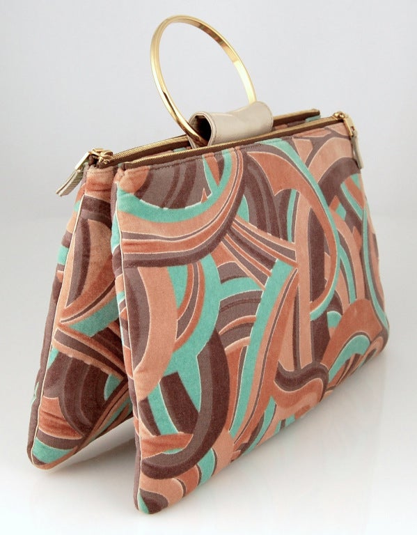 A double zip pouch handbag with a gilt metal ring handle. Fantastic colorful swirls of printed velvet in tan, raisin and aqua are raised off the background, great texture! 

Zipper pulls feature medusa head logo. One compartment has interior