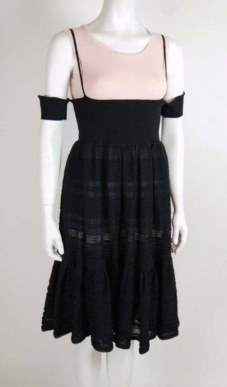 Flirty countryside-inspired black knit dress with fitted stretch waistband, spaghetti straps and off-shoulder short sleeves. Knee-length knit skirt is gathered at the waist and has a wide knit ruffle. Plastic CHANEL badge sewn on the front near