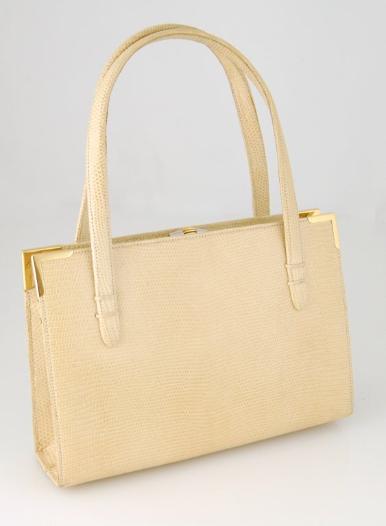 Indulge your 1950's glamour fantasies with this gorgeous Gucci handbag in light yellow lizard skin. This bag has one main compartment with 3 interior pockets and one interior zipper pocket with Gucci crest zipper pull. Beautiful sculptural clasp in