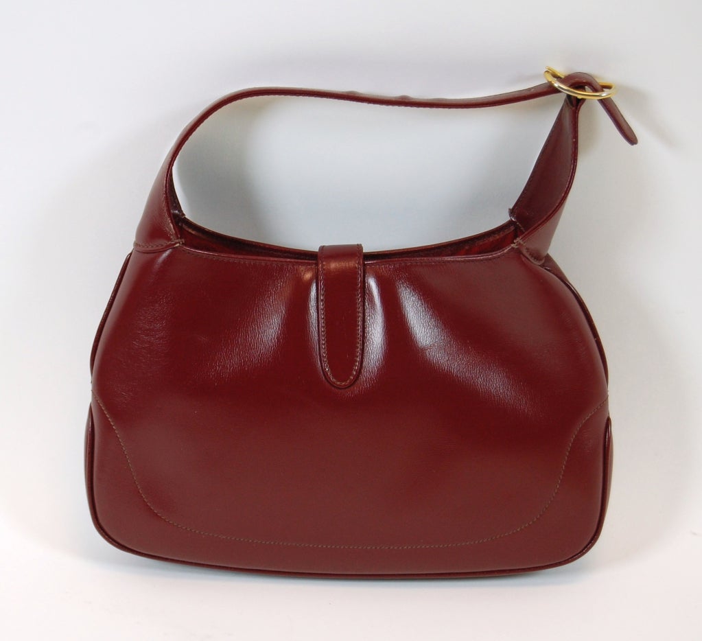 The iconic bag beloved by Jackie O, this 1960's leather Gucci bag carries an aura of timeless style and sophistication. This bag features a smooth leather outer in dark red with red suede lining. One interior zip pocket with Gucci crest zipper pull.