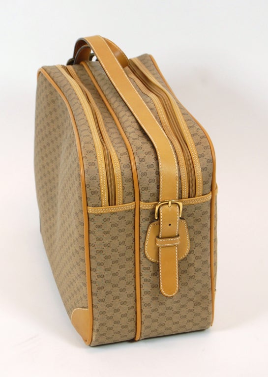 Classic travel style from Gucci. This rectangular structured bag features a coated monogram canvas exterior with tan leather trim. 2 main compartments with zip closure. One exterior pocket. Adjustable shoulder strap.