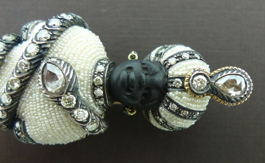 Rare example of Italian blackamoor jewelry.  Exquisite workmanship and detail.  Brooch is engraved throughout with handcarved ebony face, seed pearl turban and garment enwrapped with a diamond snake. The piece is entirely decorated with fine, full