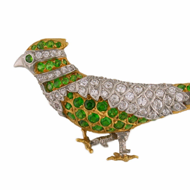 Elegant Pheasant Pin set in 18kt Yellow Gold and Platinum.  The exquisite design of pave Diamonds and Emeralds come together beautifully to create this one of a kind aviary pin. Impeccable quality offered at a conservative price, backed by Shreve,