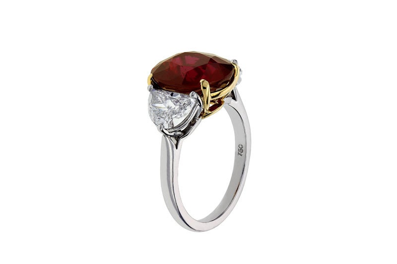 Platinum and 18 karat yellow gold 3 stone ring consisting of 1 oval shaped ruby weighing 6.05 carats, measuring 11.63 x 9.70 x 5.81 mm, with GRS certificate #GRS2009-080671T, stating a color of Vivid Red, No Heat, Mozambique origin, the center stone