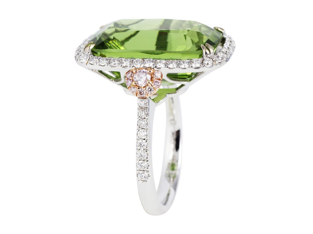 18 karat white ring consisting of 1 cushion cut peridot having weighing 14.63 carats with CDC certificate #CDC 1205104, set with .16 carats total weight of pink diamonds and .58 carats total weight of colorless diamonds.