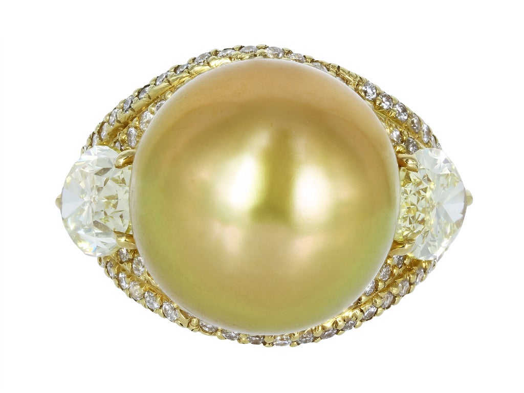 18 karat yellow gold estate ring consisting of one 14.40mm South Sea canary pearl, flanked by 2 natural oval shaped canary diamonds having a total weight of 2.89, the pearl is set with approximately .35 carats total weight of full cut diamonds