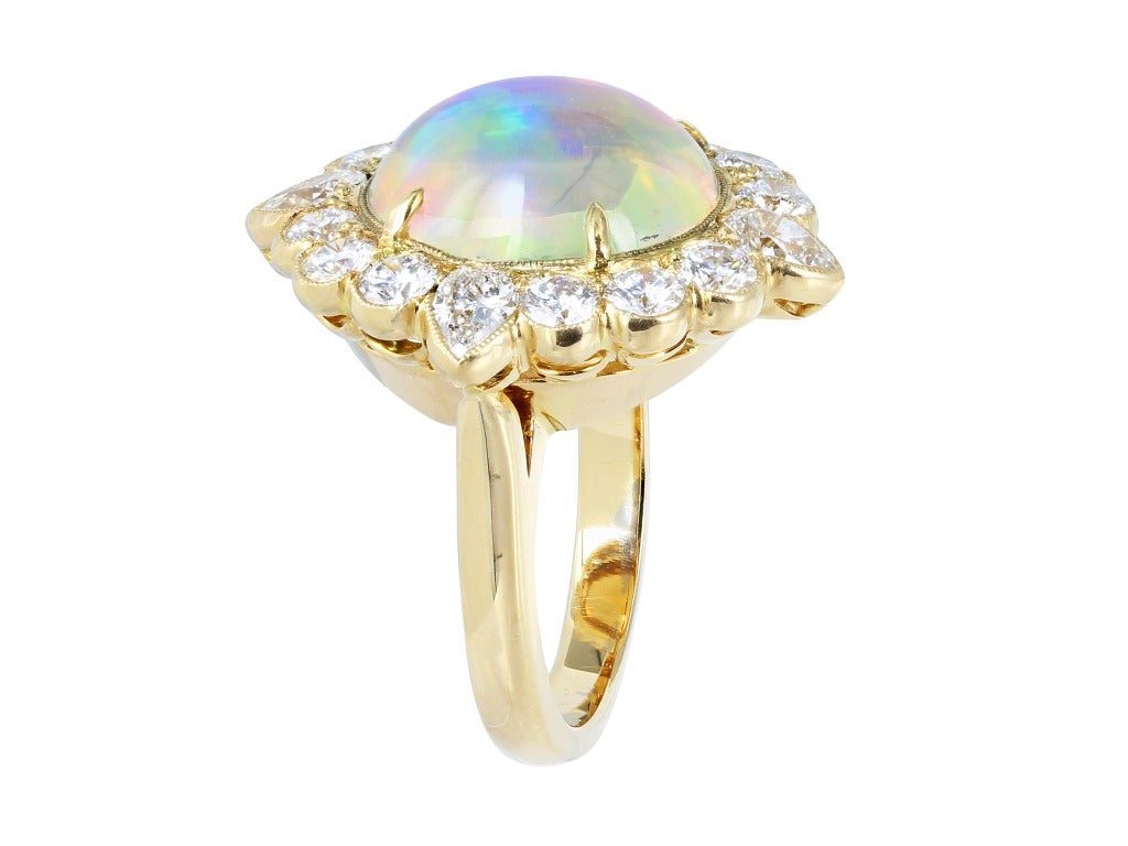 18 karat yellow gold cluster ring consisting of 1 oval shaped cabochon jelly opal weighing 6.32 carats, the center stone is set with 2.03 carats of round brilliant cut and pear shape diamond diamonds.