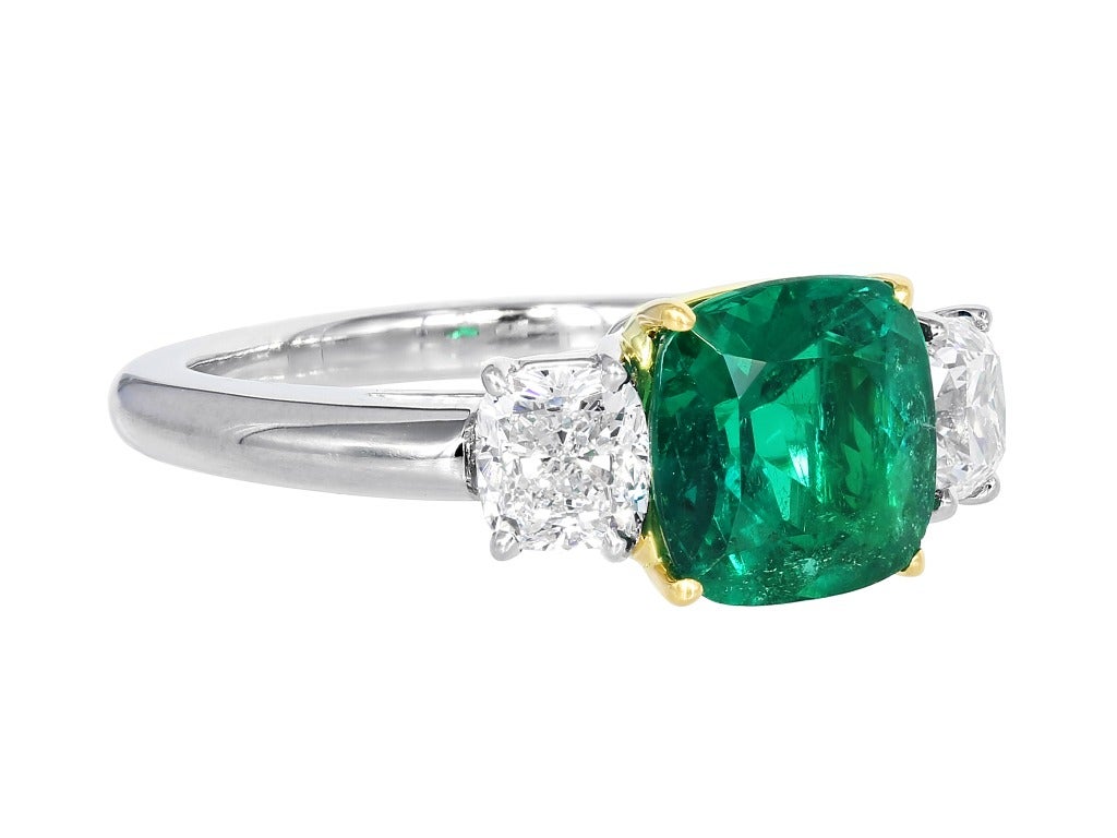Platinum and 18 karat yellow gold custom made 3 stone ring consisting of 1 cushion cut Colombian emerald weighing 1.88 carats, measuring 7.93 x 7.87 x 5.20mm with AGL certificate CS 56940. The center stone is flanked by 1 cushion cut diamond