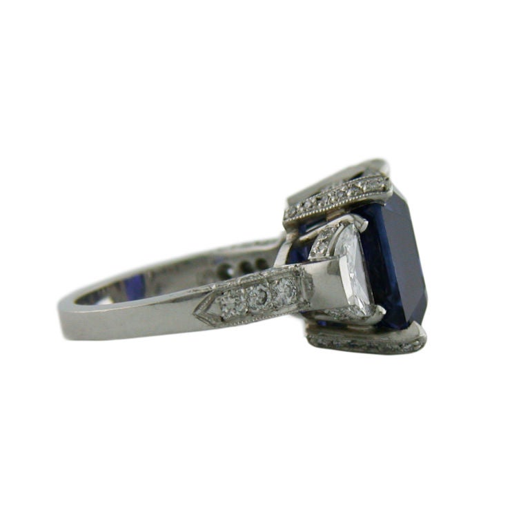 This beautiful emerald cut Sapphire of Ceylon origin is set in a solid platinum mounting.  This deep and rich blue Sapphire weighs 11.46 carats total weight and is accompanied by an AGTA certificate of authenticity. The Sapphire is accented by two