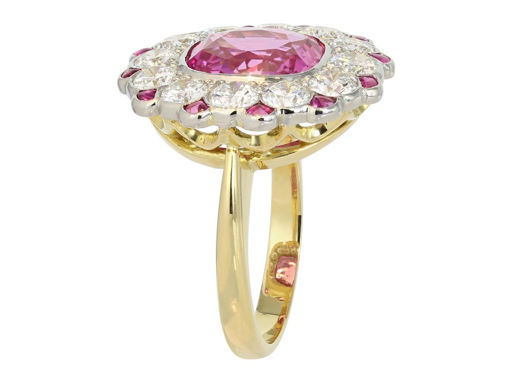 Two tone 18 karat yellow and white gold cluster ring consisting of 1 cushion cut pink sapphire weighing 4.28 carats, the center stone is set with 11 round brilliant cut diamond having a total weight of 1.83 carats and is set with custom cut pink