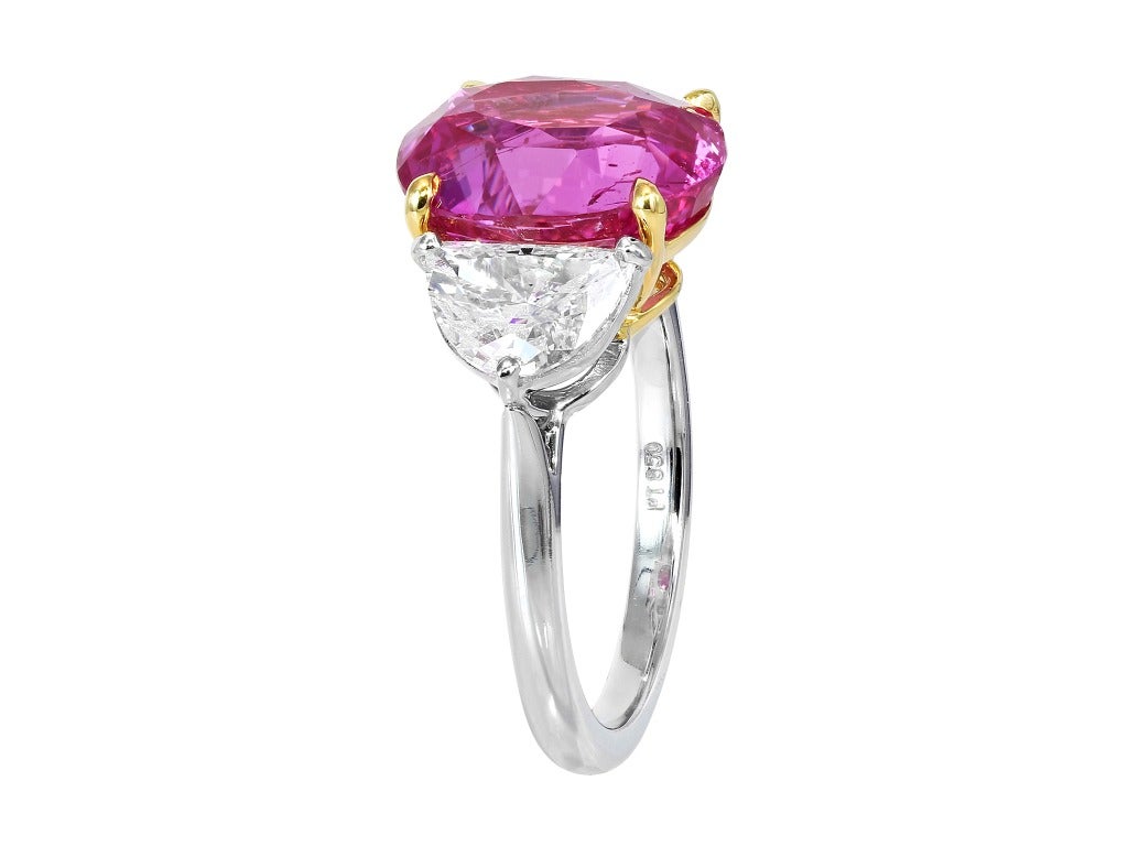 Platinum and 18 karat yellow gold custom made 3 stone ring consisting of 1 oval shape pink sapphire weighing 6.70 carats, the center stone is flanked by 2 brilliant cut half moon diamonds having a total weight of 1.37 carats.