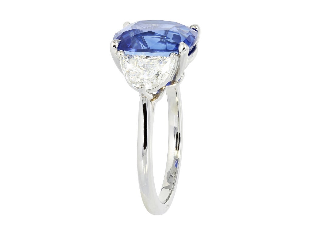 Platinum custom made 3 stone ring consisting of 1 cushion cut sapphire weighing 6.15 carats, the center stone is flanked by 2 brilliant cut half moon diamonds having a total weight of 1.29 carats.