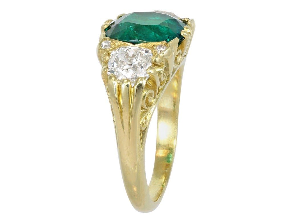 18 karat yellow gold Victorian 3 stone ring consisting of 1 cushion cut Colombian emerald weighing 3.27 carats, measuring 9.75 x 8.75 x 5.35mm with CDC certificate #1401304 stating Columbia origin, the center stone is flanked by 2 old European cut