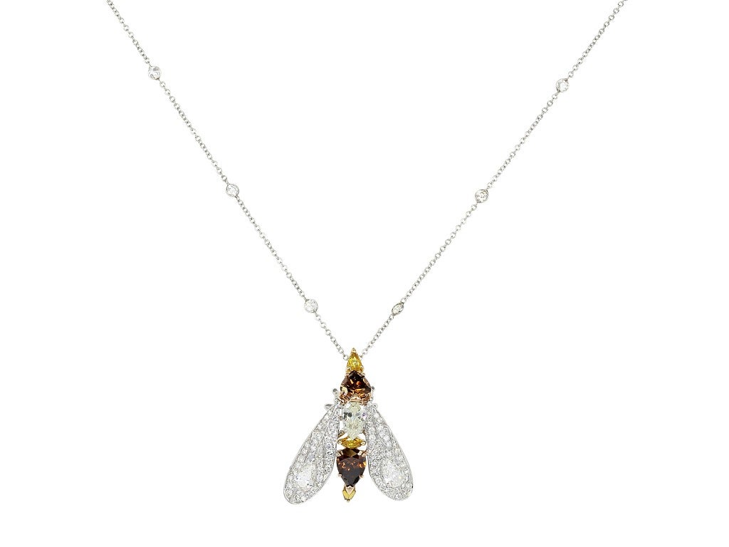 Estate Two tone 18 karat yellow and white gold insect
pendant, set with cognac color and orangish
colored diamond torso and full cut and pear shape
colorless diamond wings on an 18 karat white gold
cable link chain necklace, consisting of 13