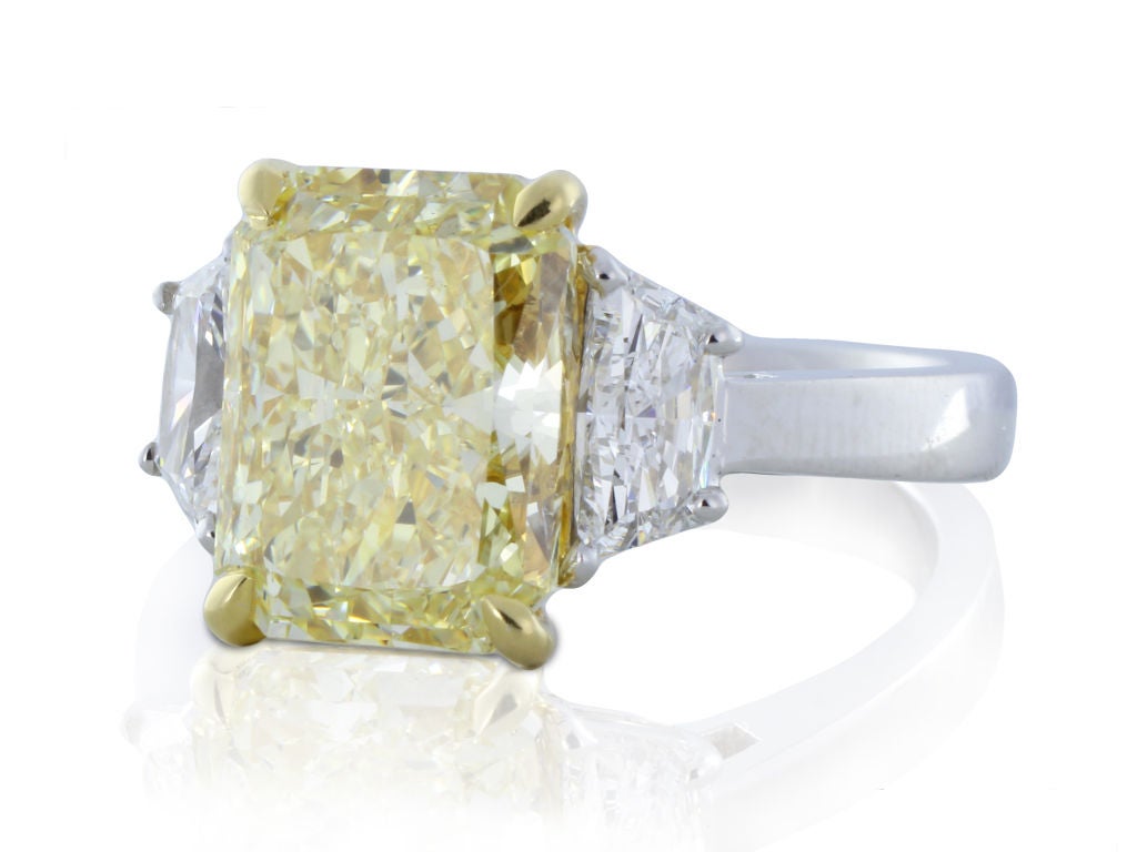 This Platinum & 18 karat yellow gold, custom made 3 stone ring features a spectacular and natural canary diamond. The center stone has a weight of 4.05 carats, a color and clarity of FY/SI1, meausring 10.31 x 7.69 x 5.34mm, with GIA certificate
