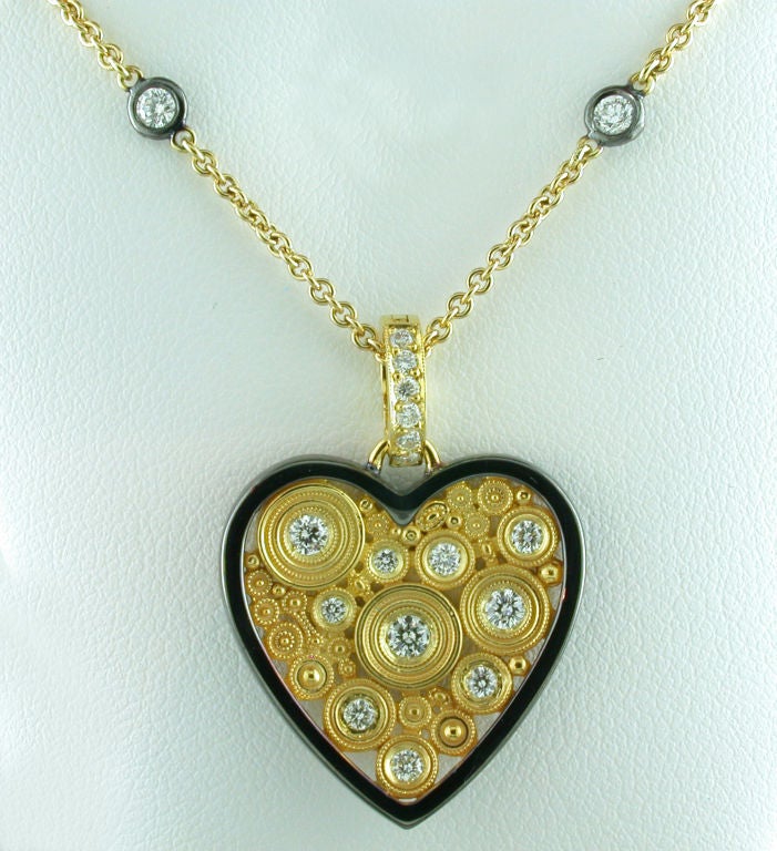 Unique heart shaped diamond enhancer pendant made of 18 karat yellow gold and black antiqued gold. The pendant is accented by .45 carats total weight of round brilliant cut diamonds waith an approximate color and clarity of F-G/VS. The pendant is