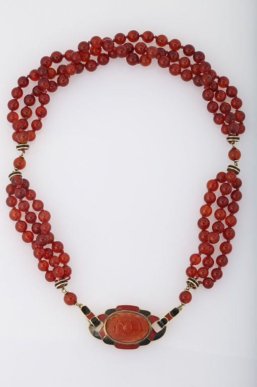 A vintage Art Deco necklace of carnelian beads with black enameled 14Kt gold rondelles and unique front clasp of 14KT gold with black and red enamel inlay, set with a carved oval carnelian. 16 inchs long.