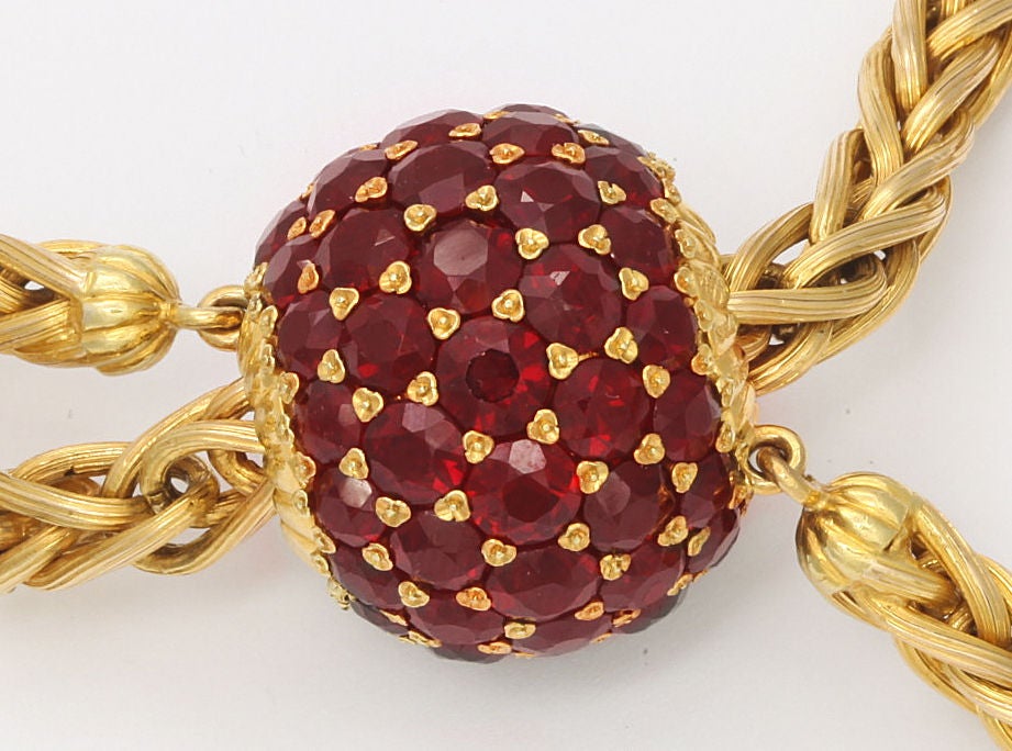 Stunning, high fashion bracelet of loosely woven 18K gold, the ends hung with large berry shape pendants set with garnets. The bracelet fit adjusted by a large ball-shape slide set with approximately 27.56cts of garnets. Italian gold marks, Abate 
