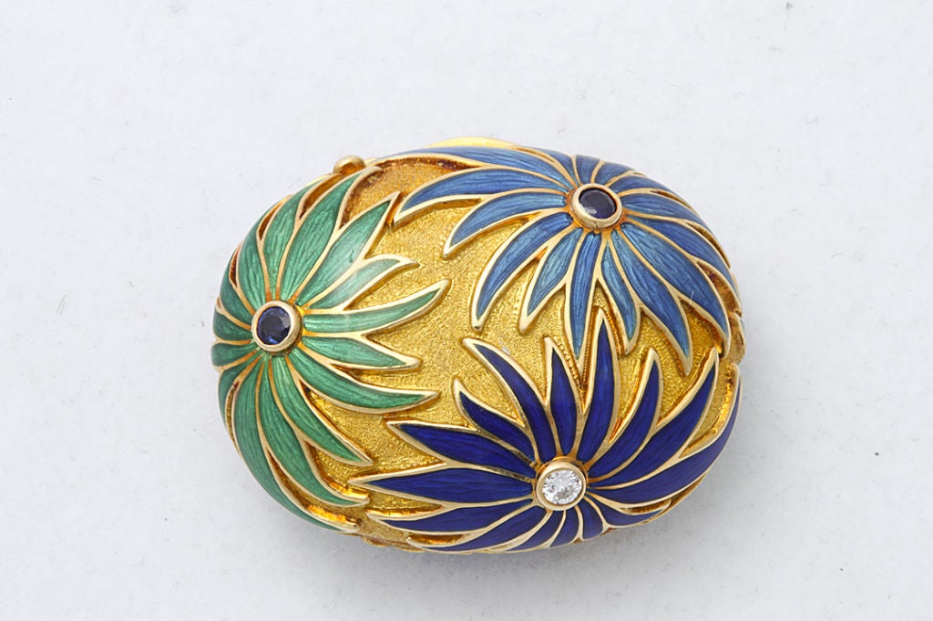Exotic Tiffany Bombay pillbox with textured 18KT gold surface, featuring three-dimensional leaves with hand detailing visible through translucent blue and green enamel, set with two diamonds and four sapphires. Tiffany Mark.