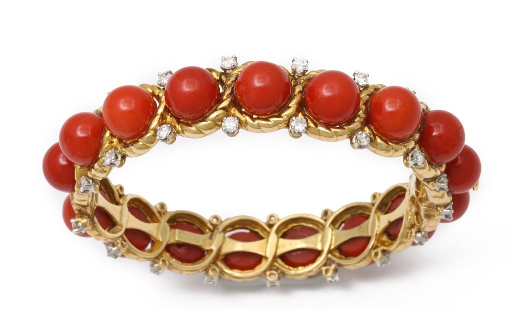 1960s Tiffany-Paris bracelet, of 18K gold rope surrounding 17 large red-orange corals (approx 9 mm), trimmed with 34 diamonds (approx 2.79 cts). Fits a 7 inch wrist. Marks: French gold mark; Tiffany and Co.; Made in France